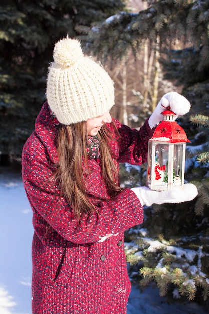 Belle jeune femme avec une lanterne de Noël rouge dans la neige