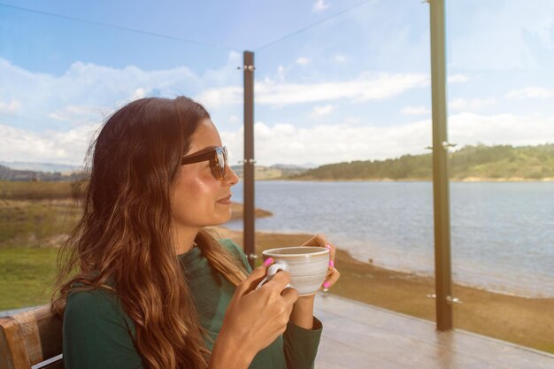 Belle jeune femme latine ayant une tasse de café à l'extérieur