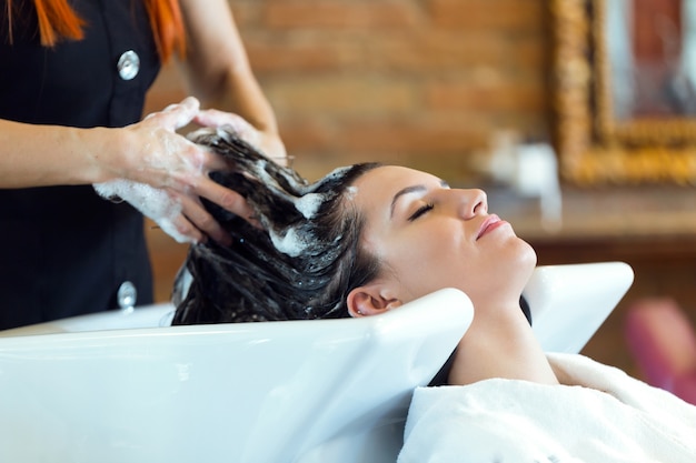 Belle jeune femme lave les cheveux dans un salon de beauté.