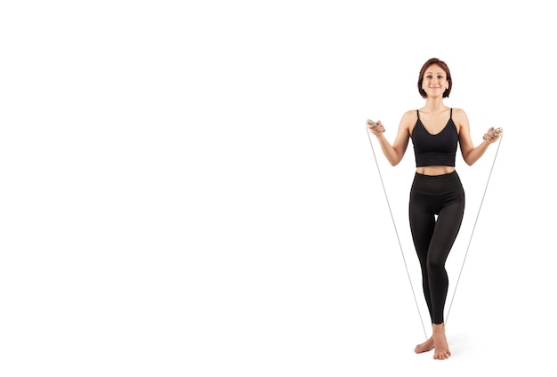 belle jeune femme en leggings noirs et haut faisant du sport et du yoga à l'intérieur