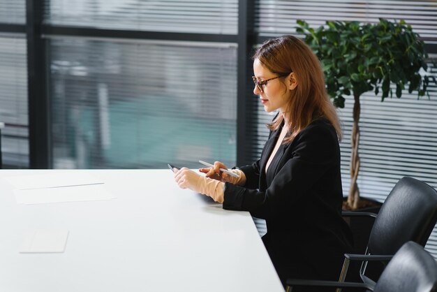 Belle jeune femme sur le lieu de travail à l'aide d'une tablette numérique