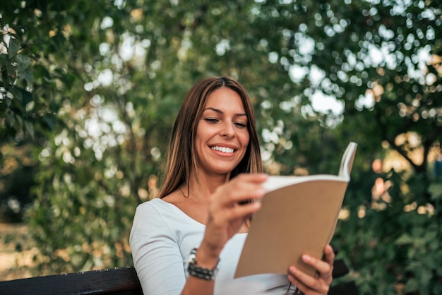 Belle jeune femme lisant un livre dans le parc.