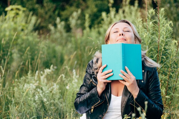 Belle jeune femme lisant un livre sur la pelouse avec le soleil.
