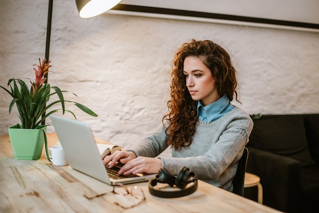 Belle jeune femme lisant le rapport sur un ordinateur portable.