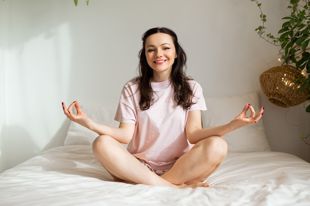 belle jeune femme sur lit dans pose d'yoga