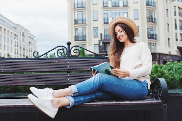 Une belle jeune femme lit un livre de papier.