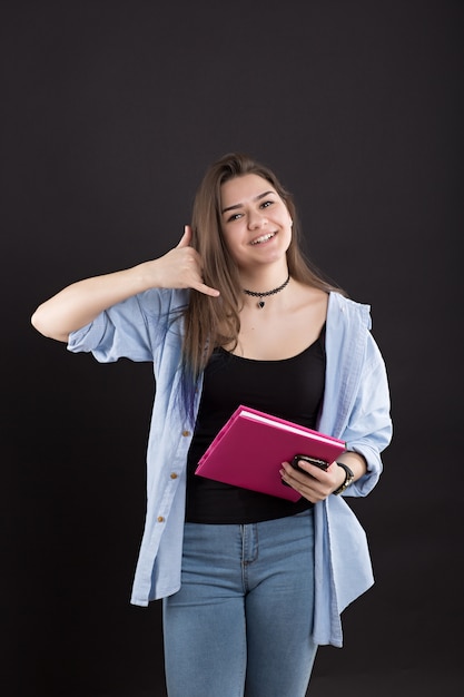 Belle jeune femme avec livre sur mur noir