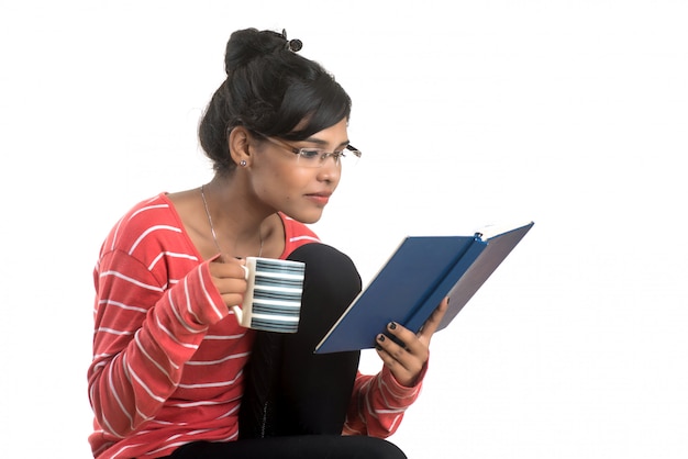 Belle Jeune Femme Avec Livre Et Tasse De Café Posant Sur Un Mur Blanc.