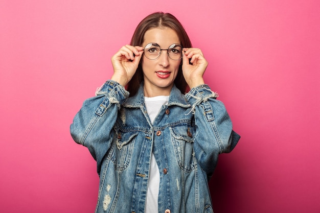 Belle jeune femme à lunettes rondes et veste en jean