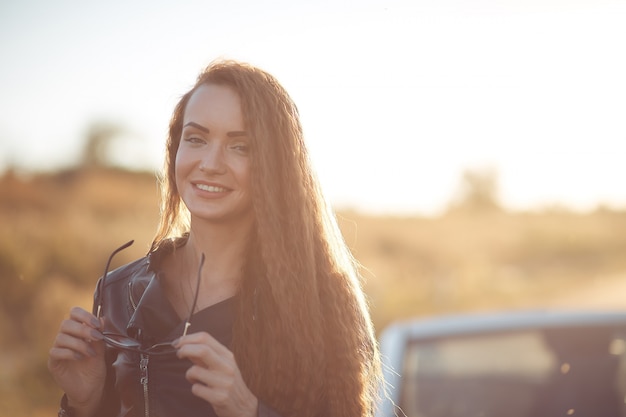 belle jeune femme à lunettes de soleil sur le ciel bleu au coucher du soleil.