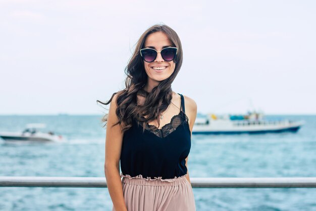 Belle jeune femme à lunettes de soleil et robe sur bateau de croisière de luxe. Femme de vacances en bateau de croisière profitant de voyages en mer. Femme heureuse gratuite regardant l'océan