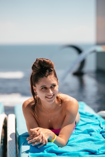 Belle jeune femme en maillot de bain prend un bain de soleil sur une chaise longue