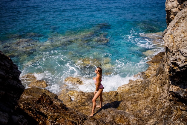 Belle jeune femme en maillot de bain se dresse sur une plage rocheuse de la mer Méditerranée. Le concept de loisirs en mer. Mise au point sélective