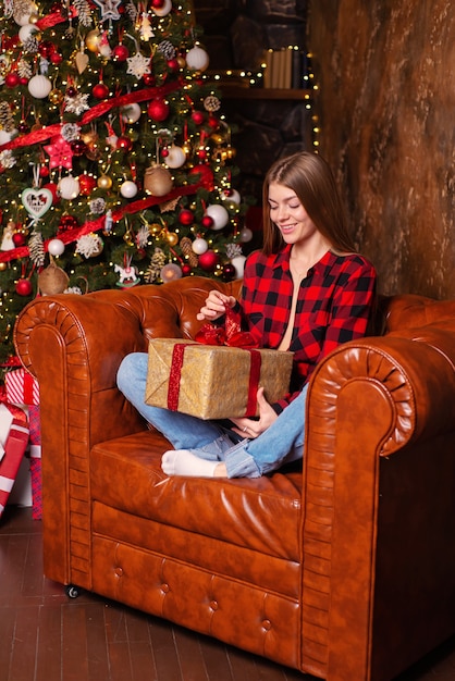 belle jeune femme à la maison à noël avec des cadeaux près de l'arbre de noël