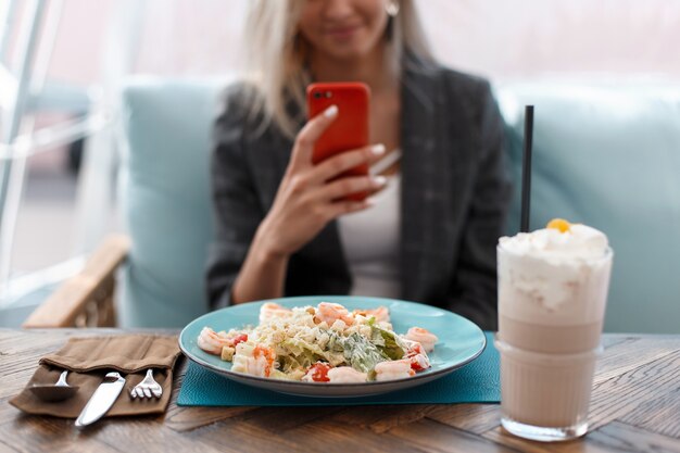 Belle jeune femme mange et prend de la nourriture photo dans un restaurant