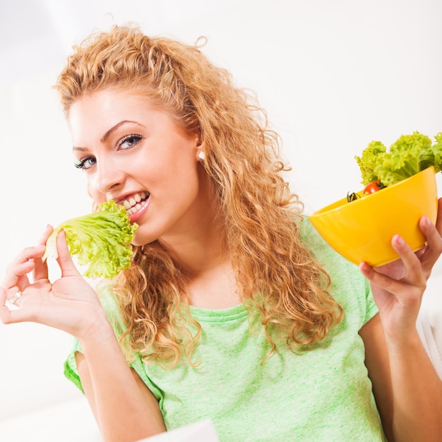 Belle jeune femme mangeant une salade