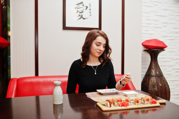 Une belle jeune femme mangeant des sushis sur un restaurant japonais traditionnel