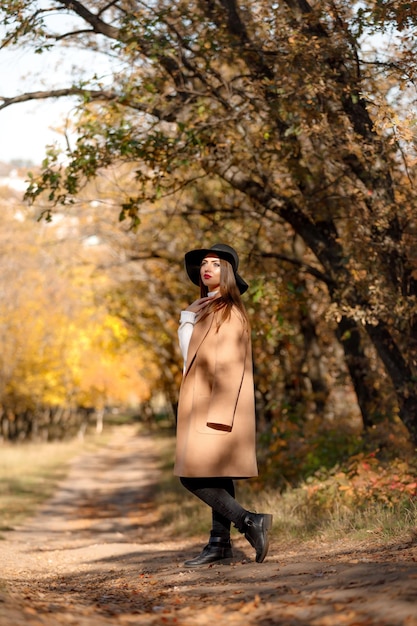 Belle jeune femme en manteau et chapeau noir