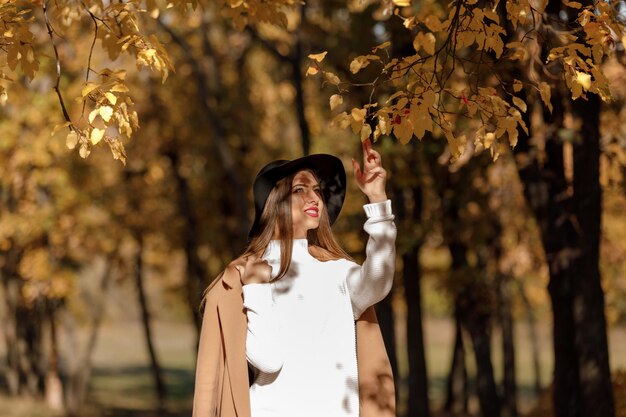 Belle jeune femme en manteau et chapeau noir