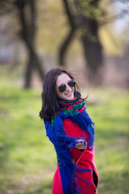 Belle jeune femme en manteau rouge et lunettes de soleil noires