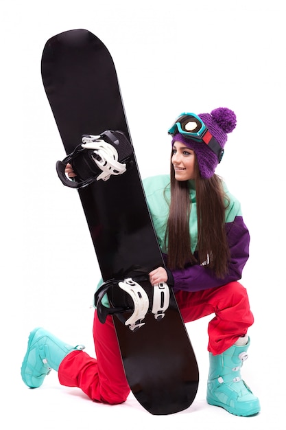 Belle jeune femme en manteau de ski violet sur genou et tenir snowboard