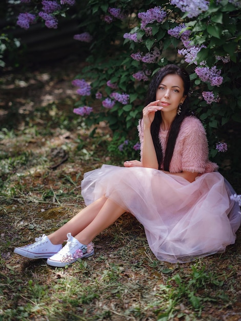 Une belle jeune femme marchant dans un jardin printanier et appréciant l'odeur du lilas. Aromathérapie et Spring Concept