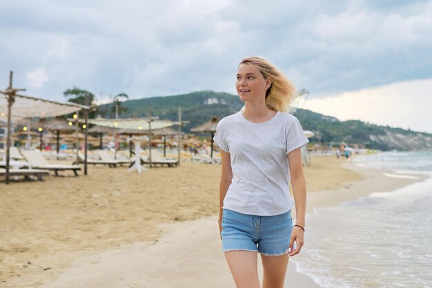 Belle jeune femme marchant le long de la plage du soir