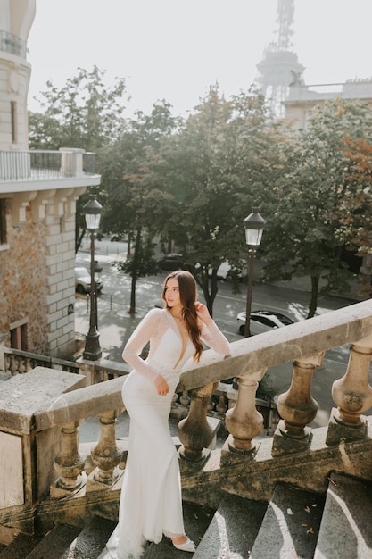 Belle jeune femme mariée brune dans une robe de mariée posant devant l'architecture