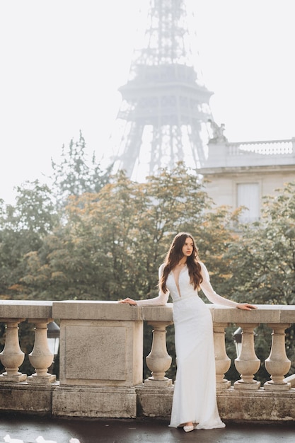 Belle jeune femme mariée brune dans une robe de mariée posant devant l'architecture