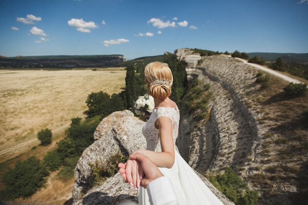 Belle jeune femme mariée tient la main d'un homme en plein air