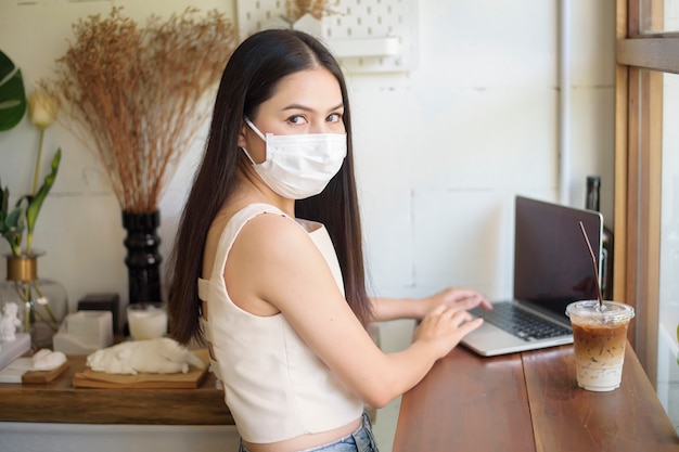 Belle jeune femme avec masque facial est assis dans un café