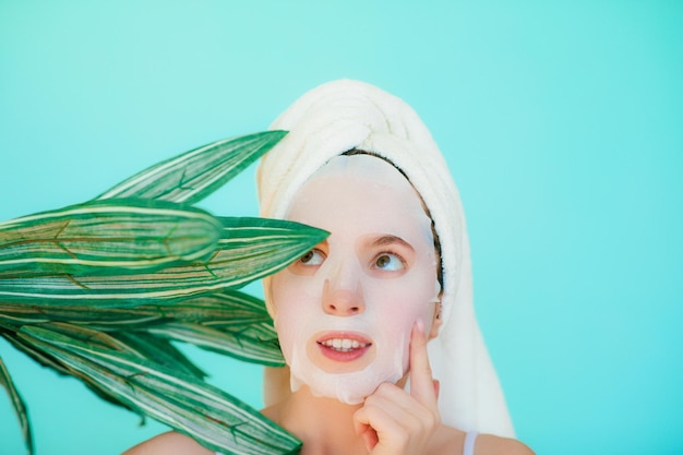 Belle jeune femme avec un masque facial sur son visage tenant des tranches de concombre.