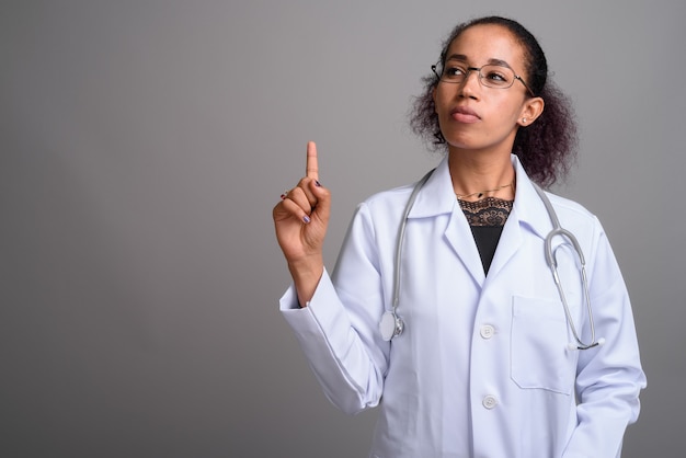 Belle jeune femme médecin africaine contre le mur gris