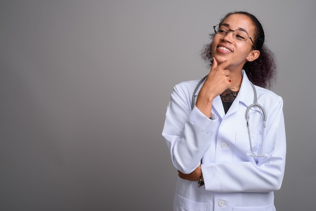 Belle jeune femme médecin africaine contre le mur gris