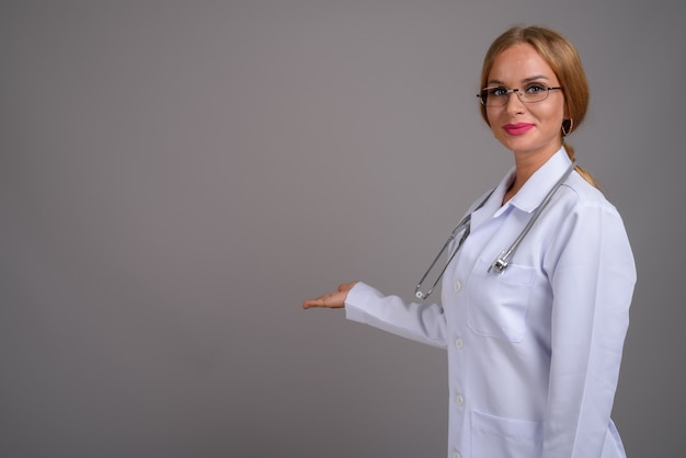 Belle jeune femme médecin aux cheveux blonds contre zone grise