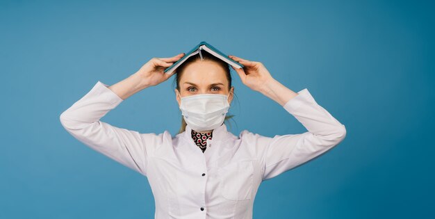 Belle jeune femme médecin en blouse de laboratoire, tourné en studio, fond bleu