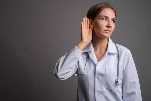 Belle jeune femme médecin contre mur gris