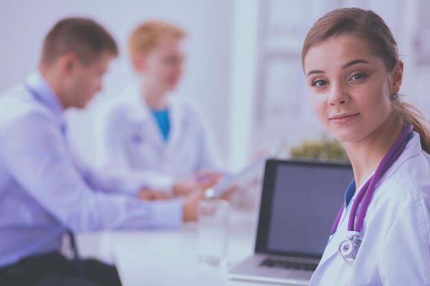 Belle jeune femme médecin souriante assise au bureau.