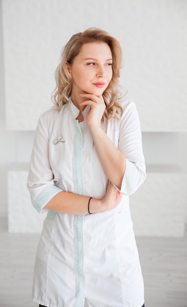 Belle jeune femme médecin en uniforme blanc posant et regardant la caméra.
