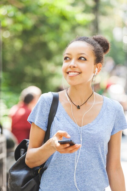 Belle Jeune Femme Métisse, écouter De La Musique Avec Des écouteurs Au Parc