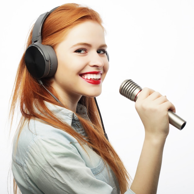 Belle jeune femme avec microphone et casque sur gris