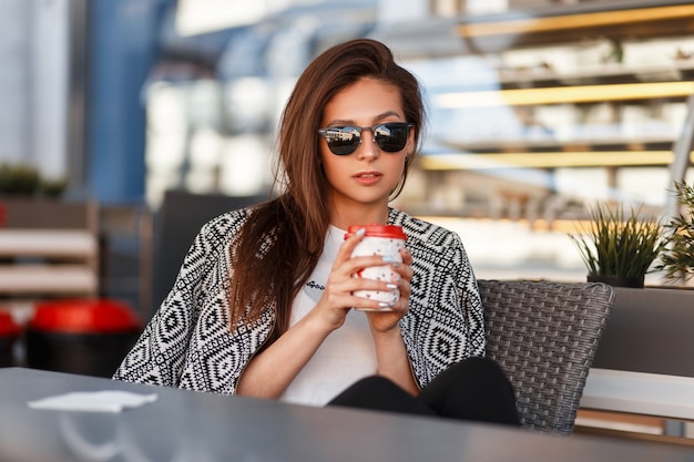 Belle jeune femme à la mode avec des lunettes de soleil dans un T-shirt blanc avec une veste de mode