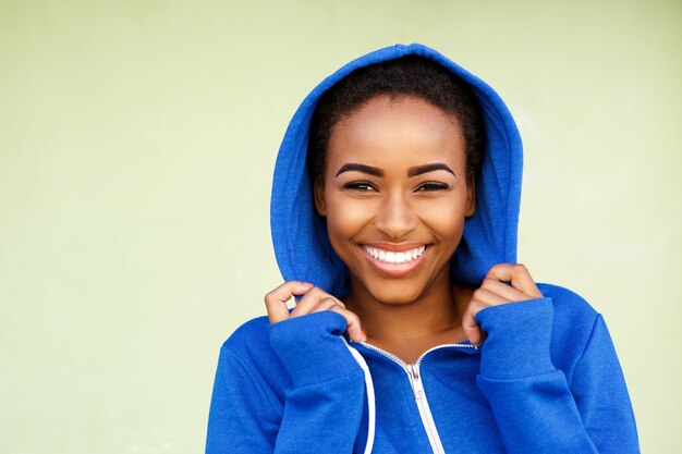 Belle jeune femme de mode noire souriante contre le mur vert