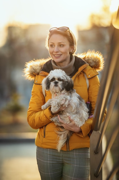 Belle jeune femme de mode passe du temps avec son mignon chien jouant dans la rue de la ville.