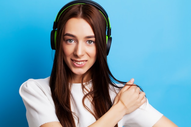 Belle jeune femme modèle écoute de la musique dans les écouteurs sur bleu