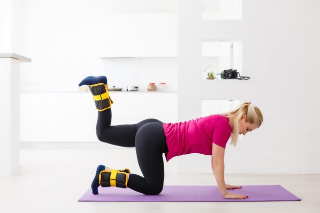 Belle jeune femme moderne athlétique fait du sport avec des poids à la maison