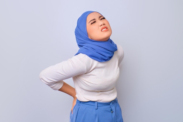 Belle jeune femme musulmane asiatique souffrant de maux de dos isolé sur fond blanc