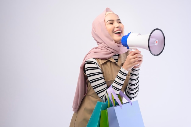 Belle jeune femme musulmane en costume tenant des sacs colorés sur fond blanc studio