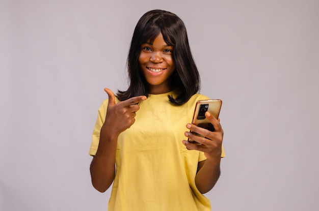 Belle jeune femme noire à l'aide de son téléphone à l'air étonné et souriant