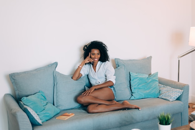 Belle jeune femme noire assise dans le canapé